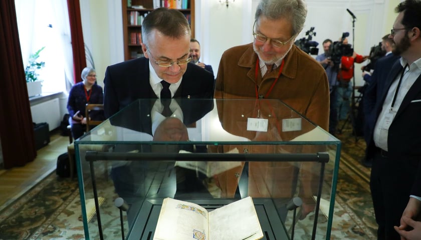 Na zdjęciu mężczyźni oglądający starą księgę. Po lewej Jarosław Sellin, wiceminister kultury, oraz Jonathan Hill, nowojorski antykwariusz