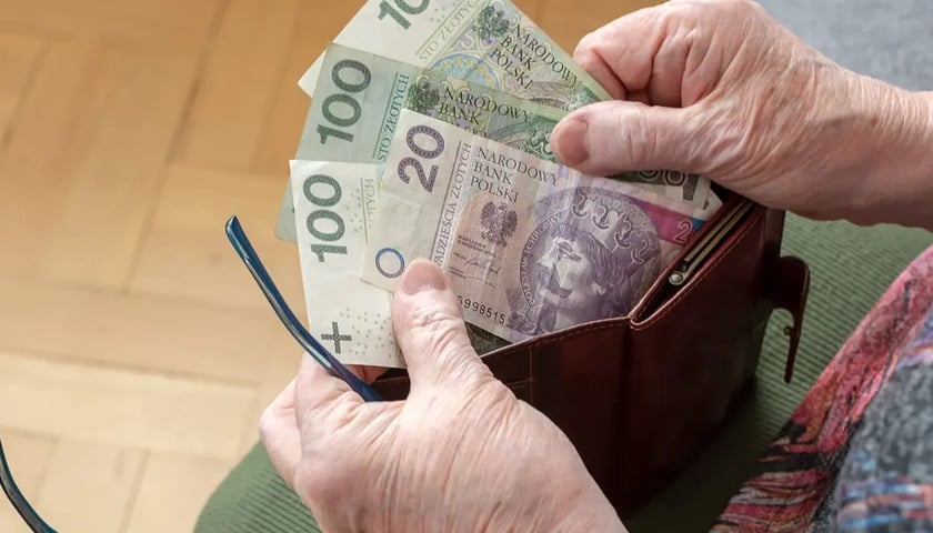 Banknoty w portfelu trzymanym w dłoniach. 