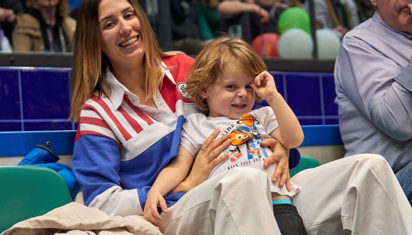Uśmiechnięta kobieta trzymająca dziecko na meczu Śląsk Wrocław - Trefl Sopot