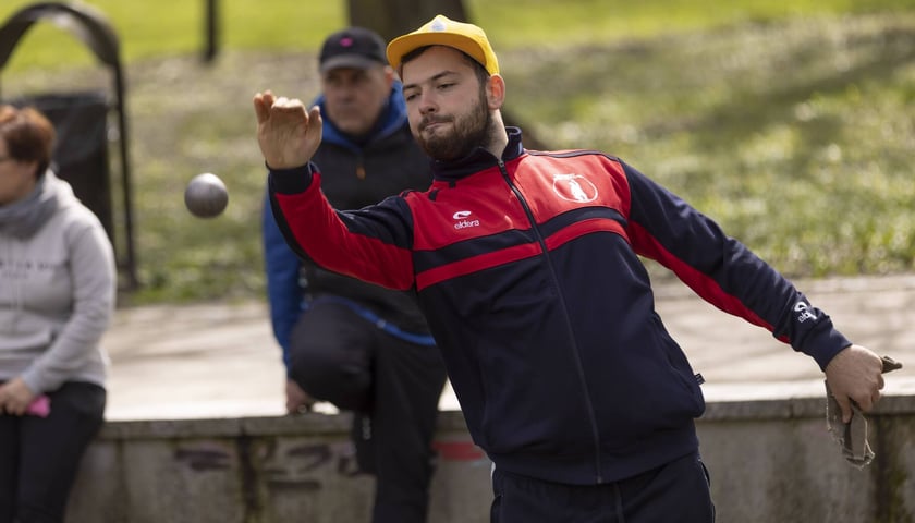 Mężczyzna gra w bule. Puchar Polski Dubletów w grze w petankę w parku Południowym we Wrocławiu