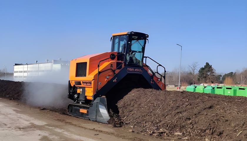 Na zdjęciu maszyna zwana przerzucarką podczas pracy przy produkcji kompostu