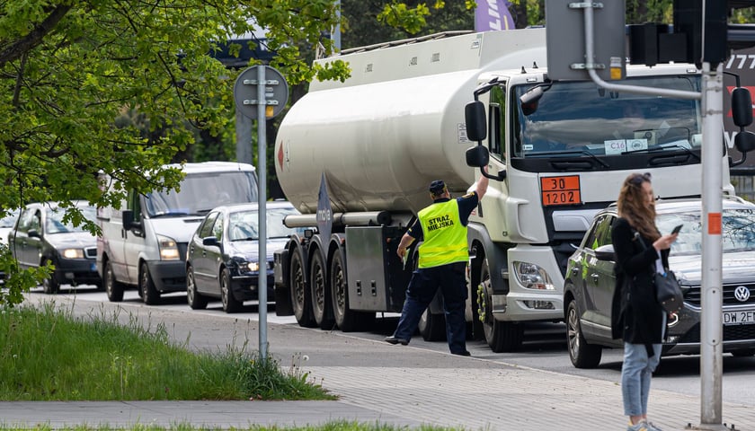 Strażnik miejski rozdaje ulotki, z której kierowcy mogą dowiedzieć się o wprowadzanym objeździe. 