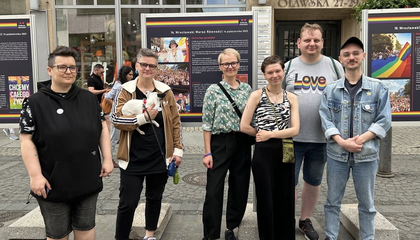 Ludzie na tle wystawy „15 lat Wrocławskich Marszów Równości” na ulicy Oławskiej