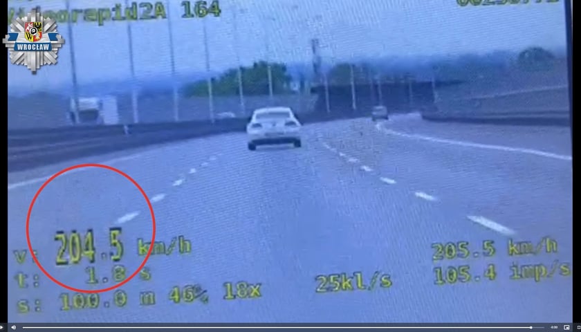 Kadr z nagrania z radiowozu, na którym widać jasny samochód jadący środkowym pasem obwodnicy. Na kadrze widać także wynik pomiaru prędkości – 204,5 km/h.