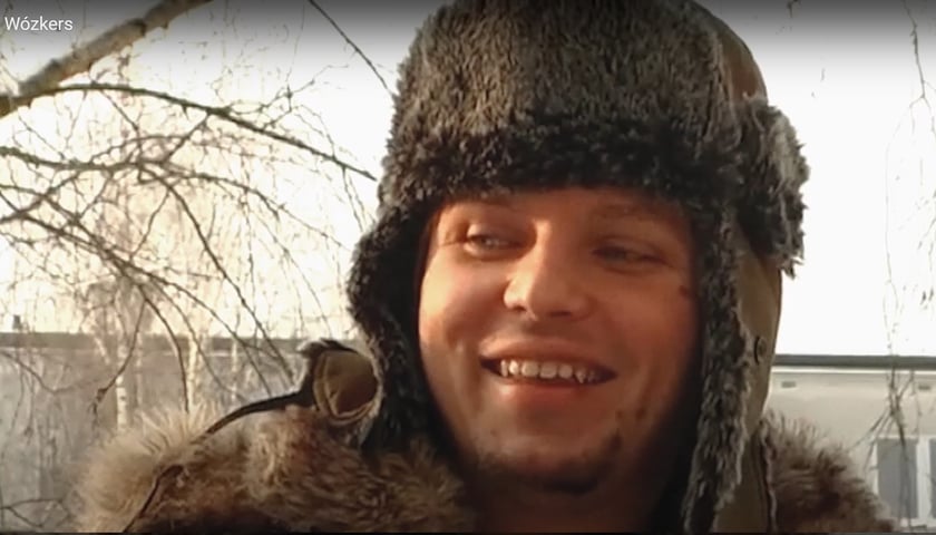 Uśmiechnięty Bartek Skrzyński w futrzanej czapie