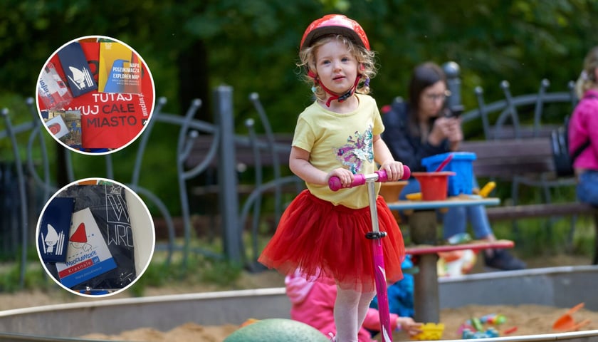 Dziewczynka na hulajnodze na placu zabaw, w dwóch kółkach miniatury gadżetów, które są do wygrania w konkursie z okazji Dnia Dziecka.
