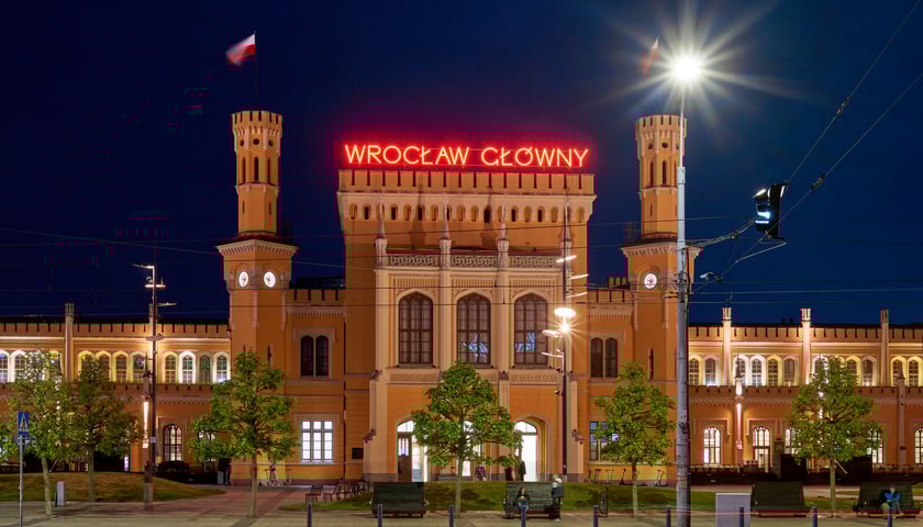 Na zdjęciu dworzec kolejowy nocą z zapalonym neonem "Wrocław Główny"
