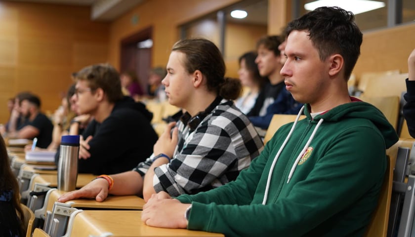 Trzej chłopcy w wieku licealnym, którzy siedzą na sali wykładowej podczas II Forum ds. Uzależnień