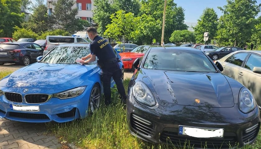 Źle zaparkowane samochody. Strażnik miejski zostawia informację o mandacie