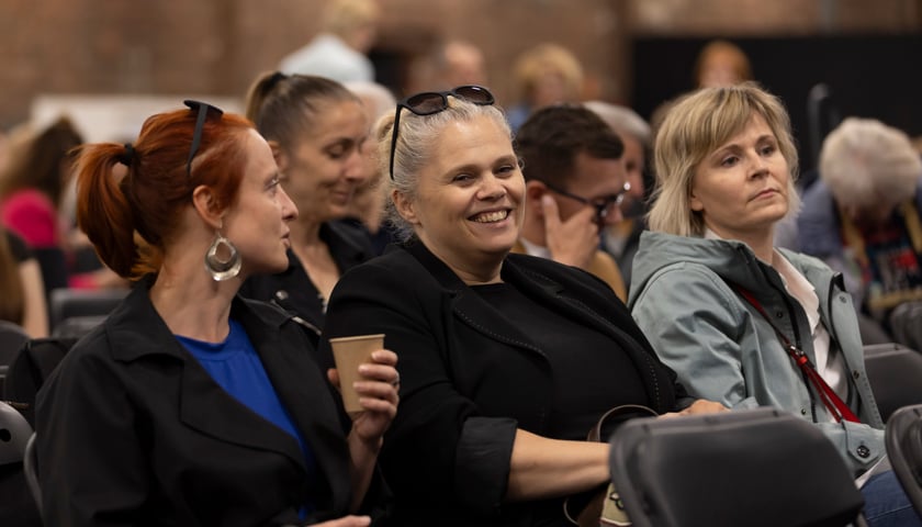 Trzy siedzące w tłumie kobiety, uczestniczki VI Kongresu Wrocławskich Organizacji Pozarządowych