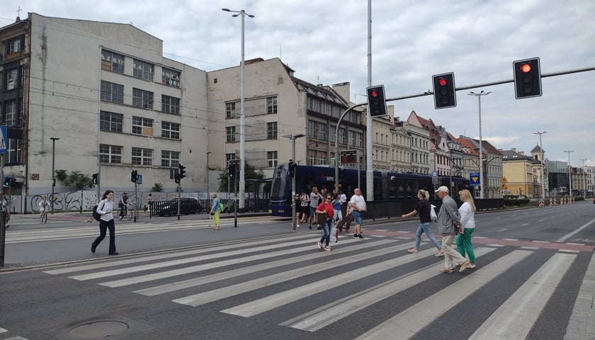 Przejście dla pieszych, przechodnie i tramwaj przy przystanku na Kazimierza Wielkiego