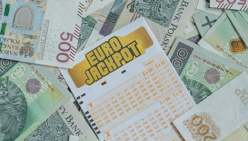 W centrum kupon Eurojackpot do skreślania cyfr, wokół banknoty o nominałach 100 zł, 200 zł, 500 zł  