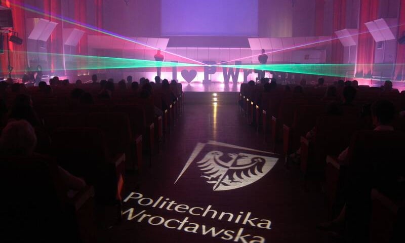 Ciemna sala, na środku godło i napis Politechnika Wrocławska 