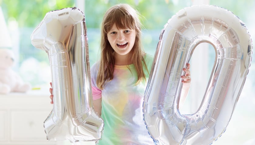 Dziecko trzyma srebrne balony: jeden i zero