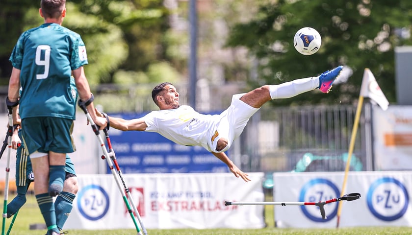 Piłkarz podczas meczu ampfutbolu strzela przewrotką na bramkę