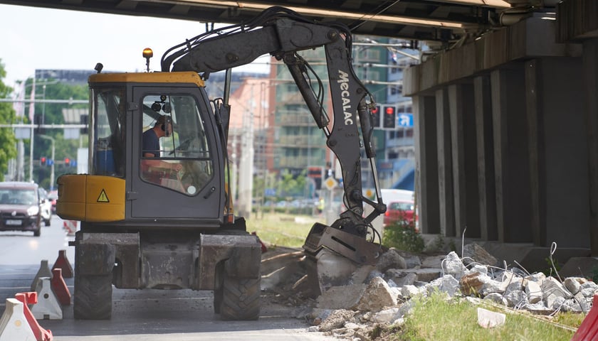 Koparka, w środku operator, w trakcie pracy na torach przy Legnickiej