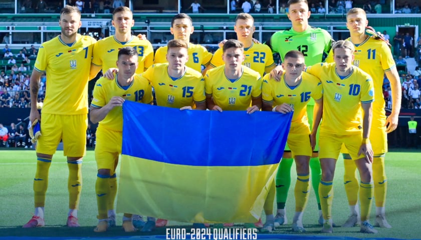 Piłkarze w żółtych strojach z flagą Ukrainy. Grafika przygotowana przez Ukraińską Federację Piłkarską.