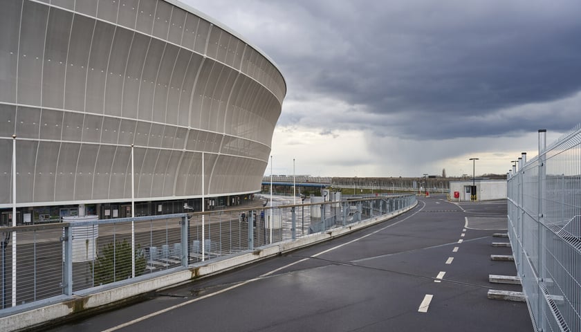 Po prawej fragment okrągłej budowli - Tarczyński Arena; po lewej fragment jezdni i płot z siatki (zdjęcie ilustracyjne)
