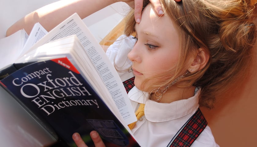 Dziewczyna czytająca słownik języka angielskiego (zdjęcie ilustracyjne)