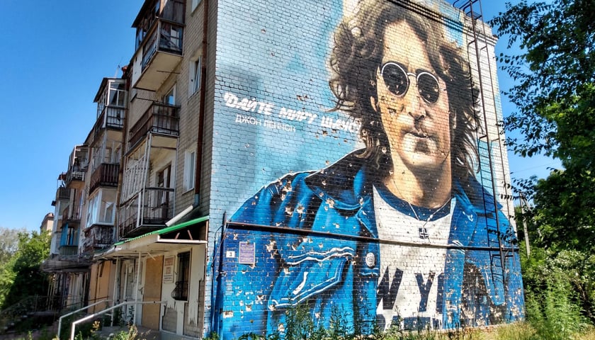 Mural z Johnem Lennonem w Izumie.  Na twarzy i ciele artysty są ślady po kulach.