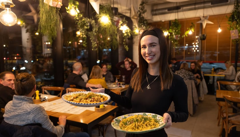 Uśmiechnięta kelnerka z potrawami na talerzach w Ragu Pracownia Makaronu