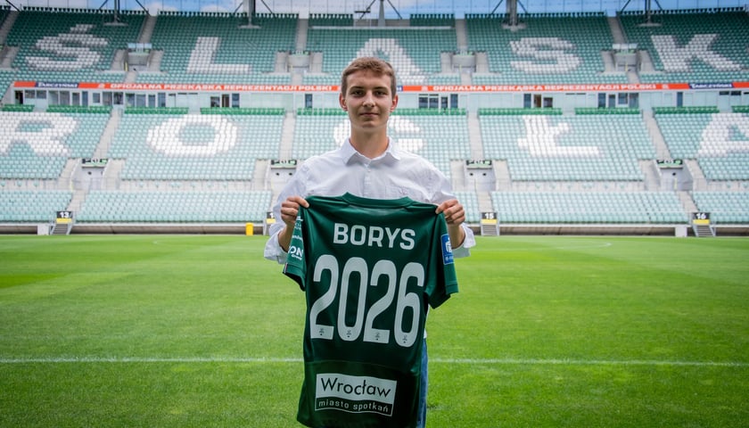 Karol Borys z koszulką ze swoim nazwiskiem i numerem 2026 stojący na murawie Tarczyński Arena