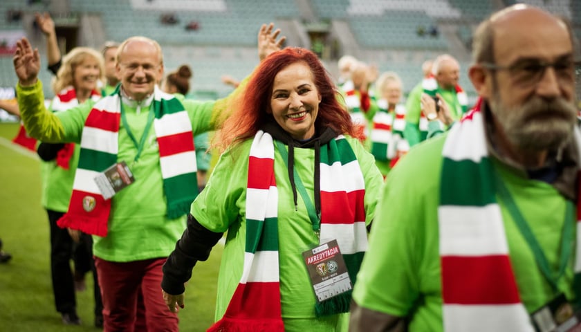 Eskorta seniorów dla piłkarzy Śląska Wrocław na Tarczyński Arenie. Wszyscy mają zielone koszulki i biało-czerwono-zielone szaliki
