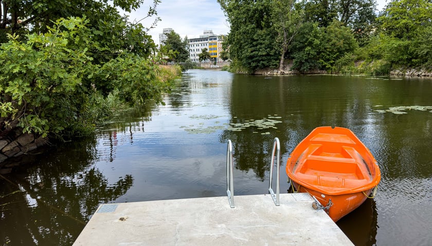 Fragment betonowego pomostu, Odra i pomarańczowa łódka w Porcie Węglowym. W tle zielone drzewa