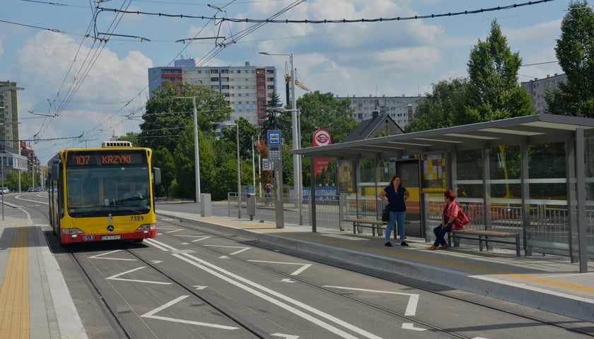 Autobus 107 zatrzymujący się przy przystanku na Nowym Dworze (TAT) i dwie kobiety pod wiatą przystankową