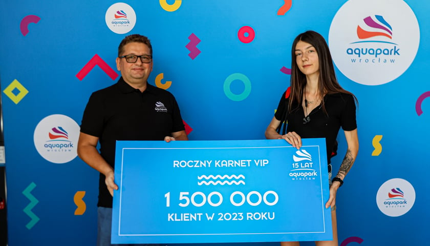 Mężczyzna i kobieta trzymają planszę z napisem roczny karnet vip, 1 500 000 klient w 2023 roku