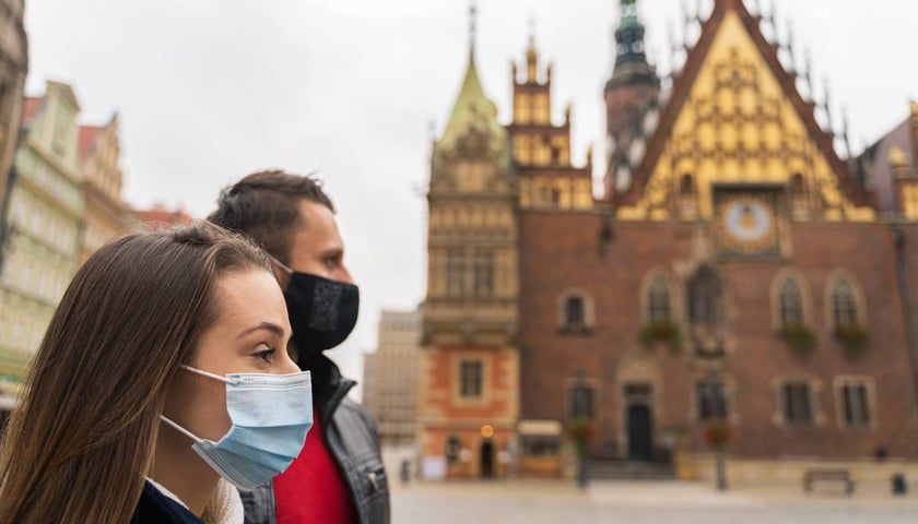 Kobieta i mężczyzna w maseczkach podczas pandemii Covid-19, w tle wrocławski Ratusz. Zdjęcie ilustracyjne
