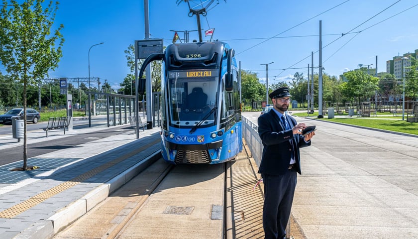 Niebieski tramwaj na trasie TAT przy ul. Rogowskiej oraz motorniczy Tomasz Sielicki, który stoi na torach