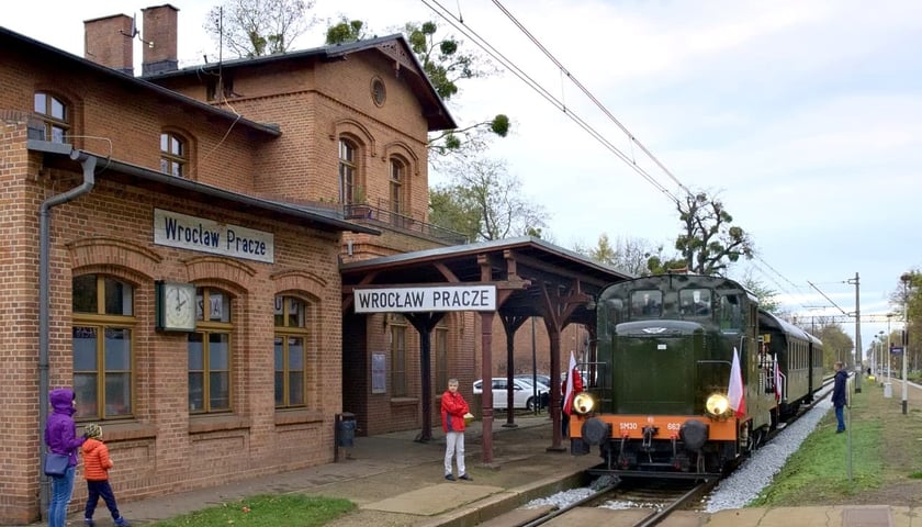 Pociąg stoi na stacji Wrocław Pracze. Po lewej stronie widać budynek stacji, po prawej - pociąg