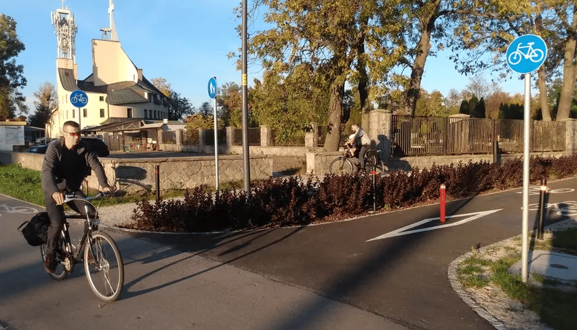 Z lewej młody mężczyzna w czarnym stroju na rowerze