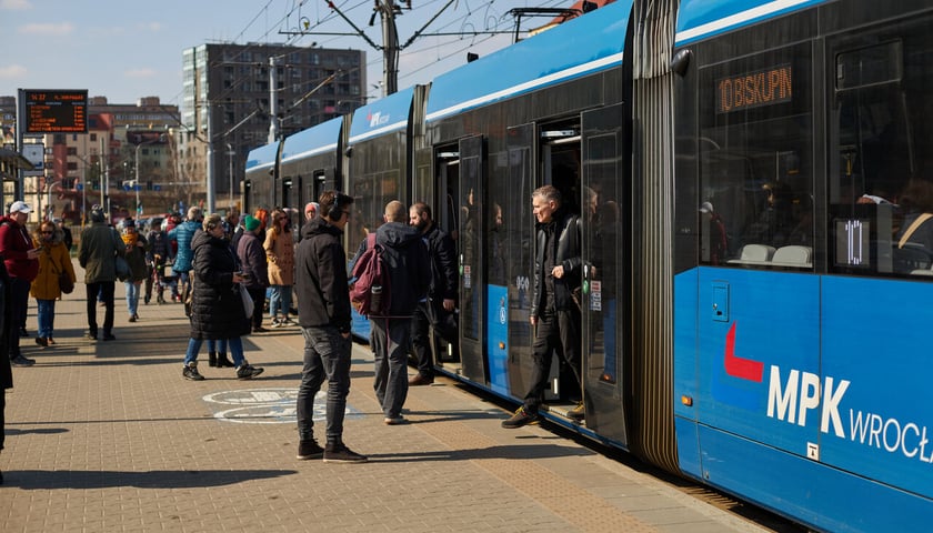Do niebieskiego tramwaju z napisem MPK Wrocław wsiadają pasażerowie 