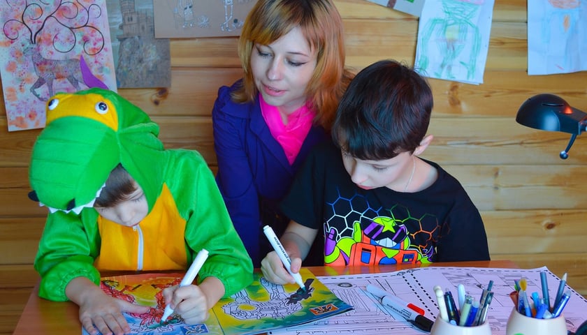 Kobieta z bawiącymi się dziećmi przy stole. Zdjęcie ilustracyjne