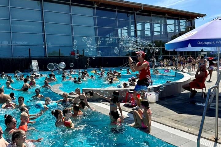 Instruktor nad basenem animuje zabawy dla dzieci i ich rodziców w wodzie