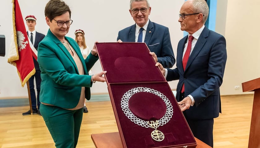 Trzy osoby, w tym prof. Piotr Ponikowski (rektor Uniwersytetu Medycznego we Wrocławiu) trzymają otwarte pudełko z insygnium uczelni na otwarciu filii w Wałbrzychu