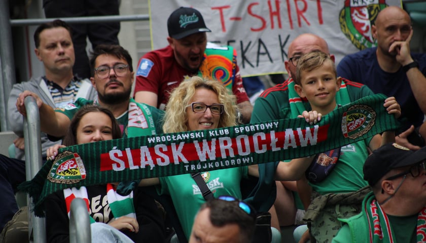Kobieta i dziecko trzymają szalik Śląska Wrocław i dopingują podczas meczu z Piastem Gliwice