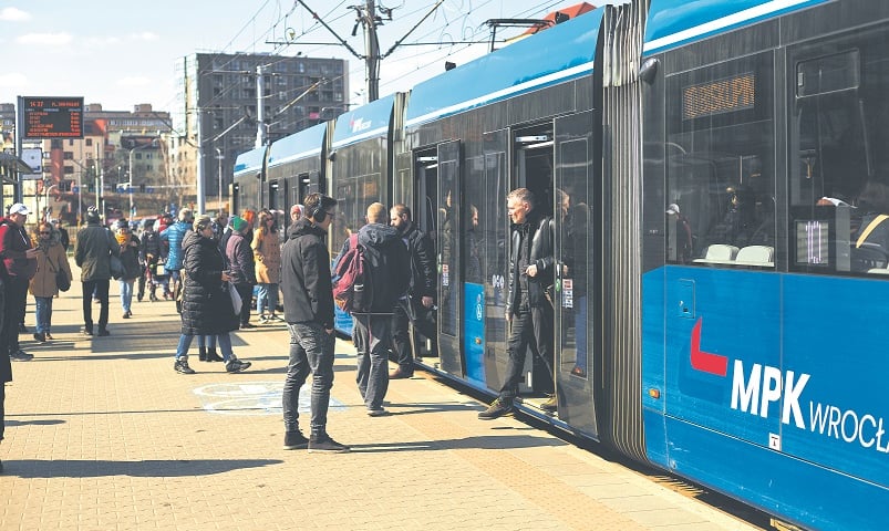 Na zdjęciu pasażerowie wsiadają i wysiadają z niebieskiego tramwaju