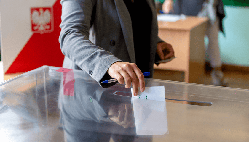 Na zdjęciu widać mężczyznę wrzucającego kartę do urny wyborczej
