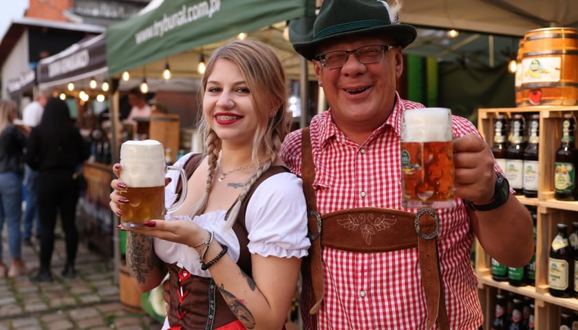 Kobieta i mężczyzna w bawarskich strojach w rękach mają kufel piwa