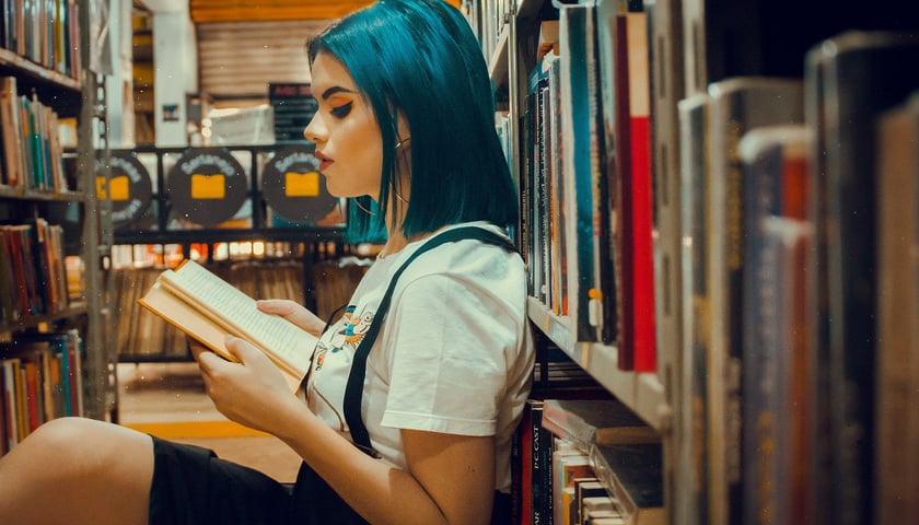 Kobieta czyta książkę w bibliotece