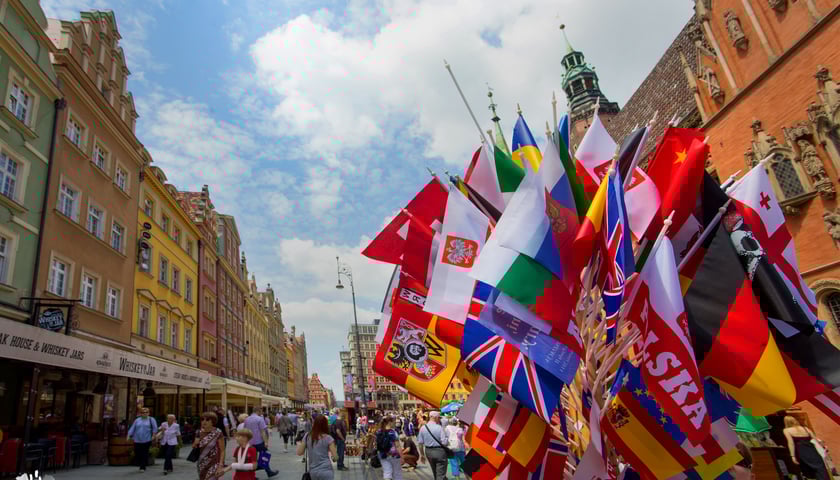 na zdjęciu flagi różnych państw na tle zabytków
