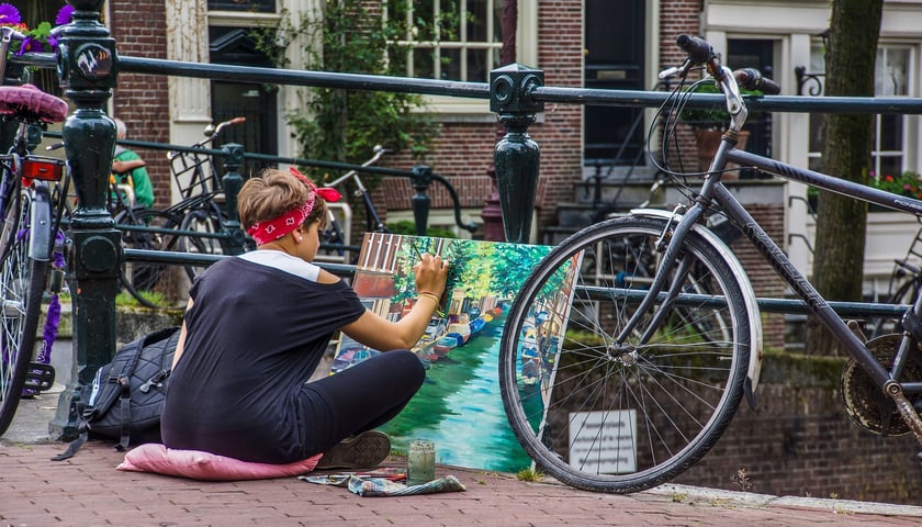 Kobieta malująca na ulicy w Amsterdamie, rowery