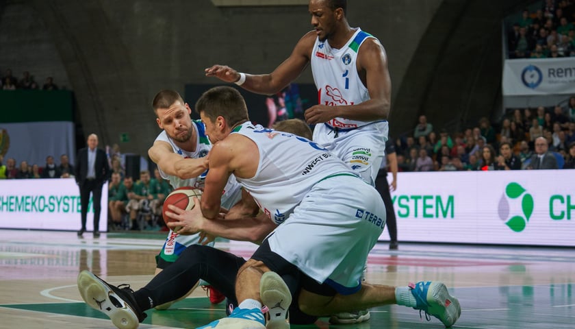 Koszykarze Śląska i Anwilu walczą o piłkę w parterze podczas meczu w hali Stulecia