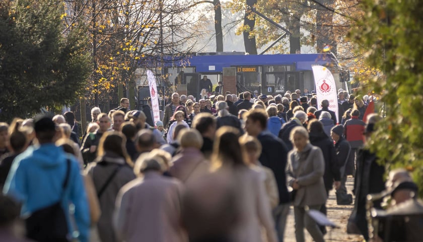 Tramwaj specjalny E1 przy cmentarzu Osobowickim oraz grupa przechodniów. 