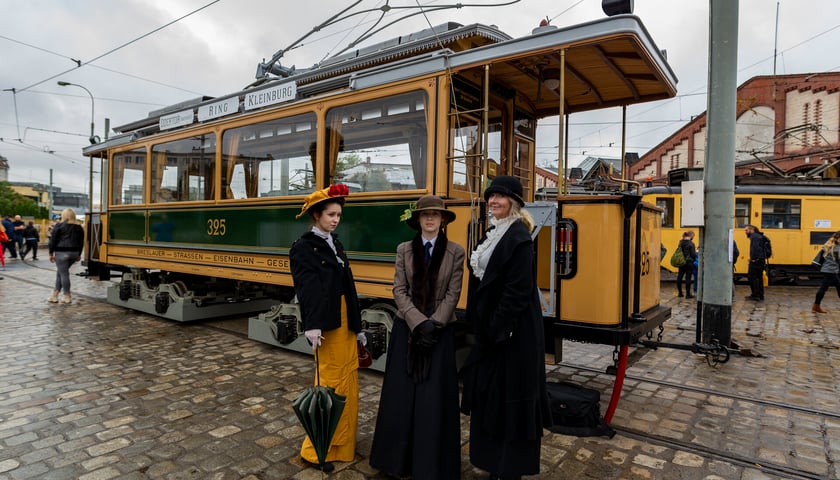 Odrestaurowany tramwaj typu Maximum z 1901 roku, na pierwszym planie trzy kobiety w strojach z epoki.