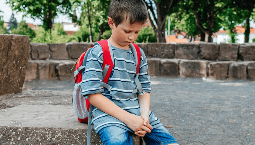 Na zdjęciu smutny chłopiec w szkolnym wieku