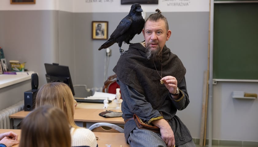 Nauczyciel Dawid Graczyk z oswojonym krukiem na ramieniu podczas lekcji historii w IV LO przy ul. Świstackiego we Wrocławiu
